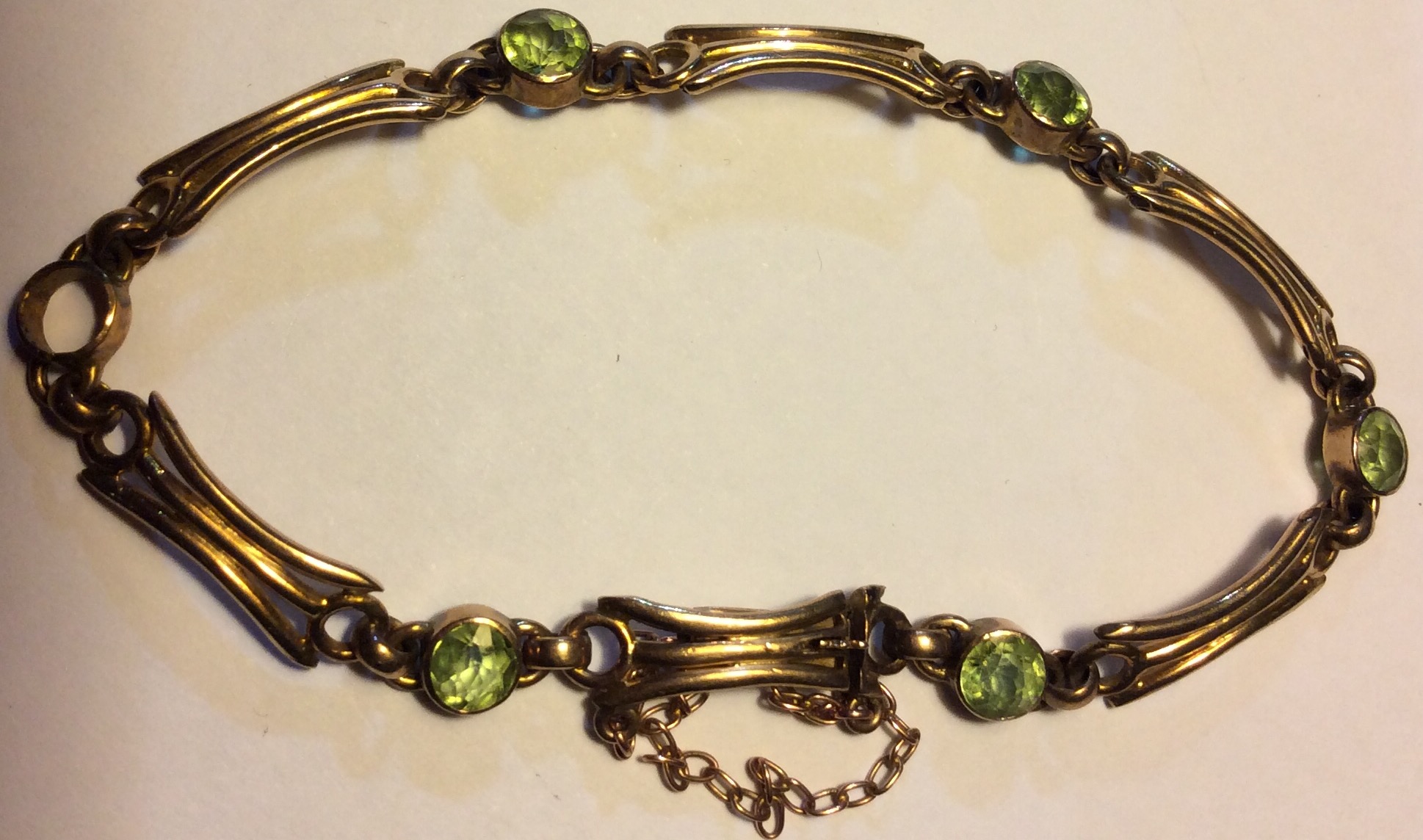 A VICTORIAN 9CT GOLD AND PERIDOT BRACELET Having links of pierced design interspersed with round cut