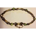 A VICTORIAN 9CT GOLD AND PERIDOT BRACELET Having links of pierced design interspersed with round cut