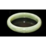 A CHINESE GREEN CELADON JADE BANGLE Of plain circular form, with white inclusions. (inner w 6cm)