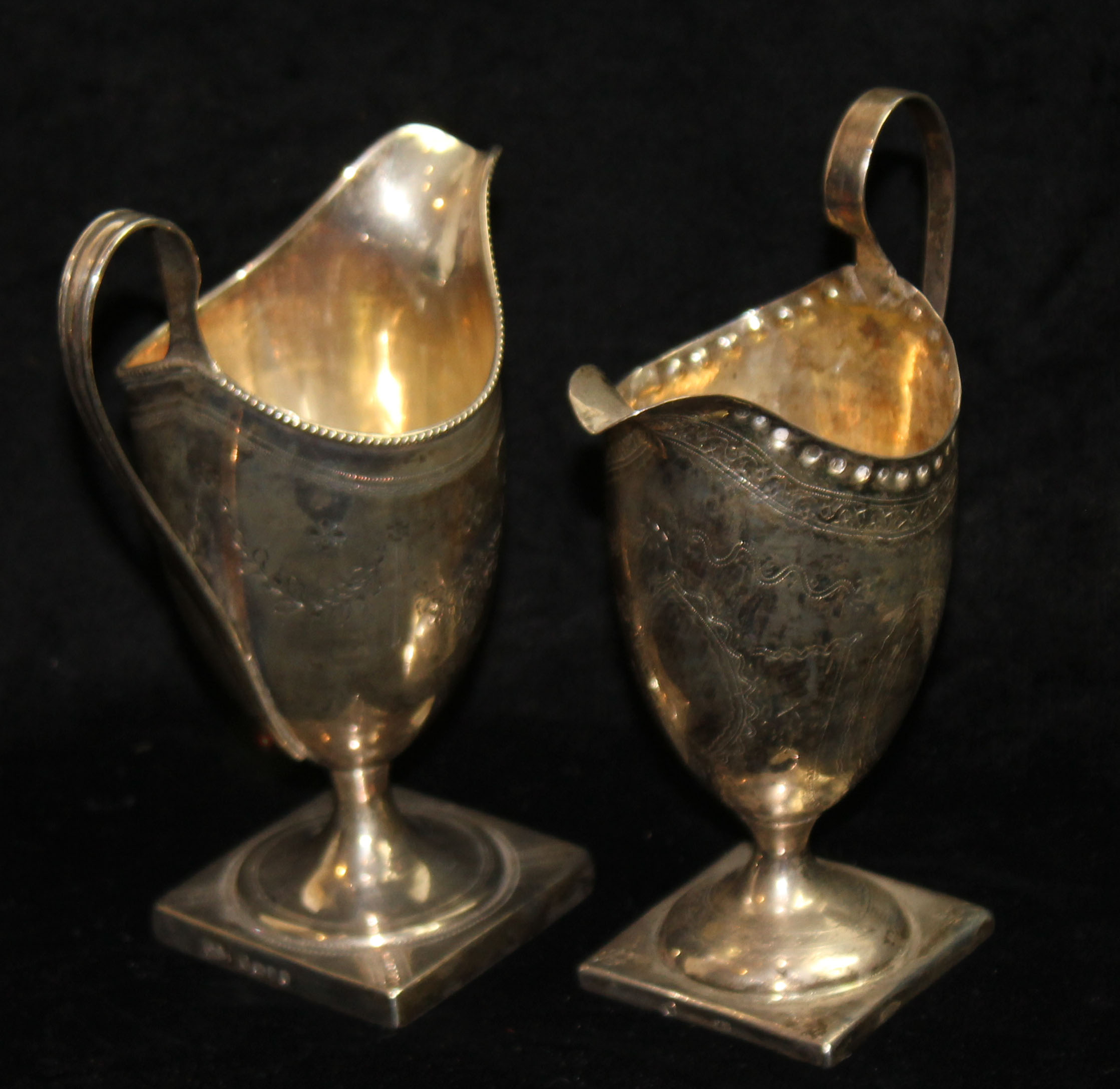 TWO GEORGIAN SILVER CREAM JUGS OF NEOCLASSICAL STYLE To include one helmet form with loop handle and