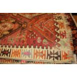 AN AFGHAN WOOLLEN RUG OF CARPET PROPORTIONS Red field with decorative motifs, constructed from two