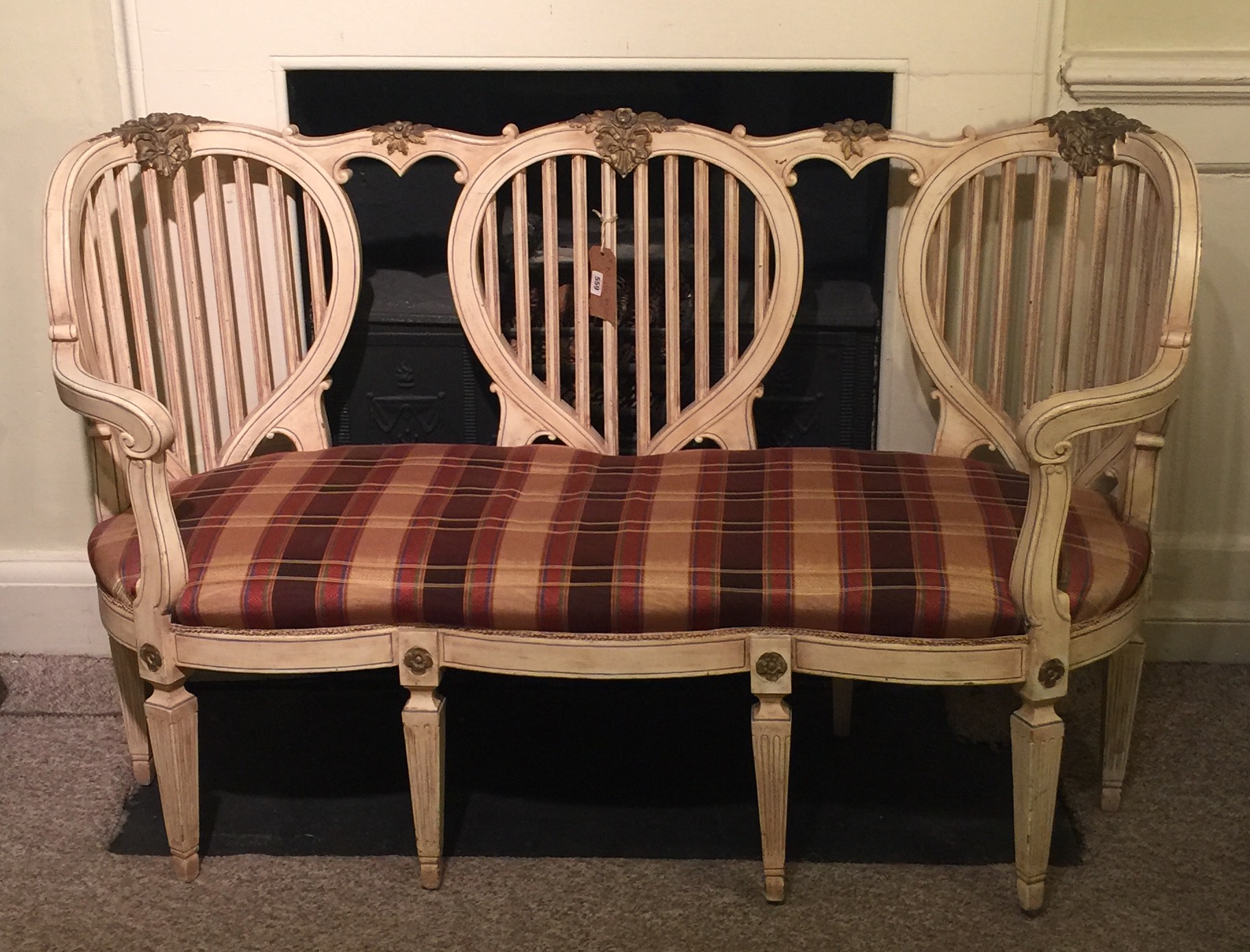 A CONTINENTAL CREAM AND GILT LOVESEAT With three lyre back and upholstered serpentine seat, raised