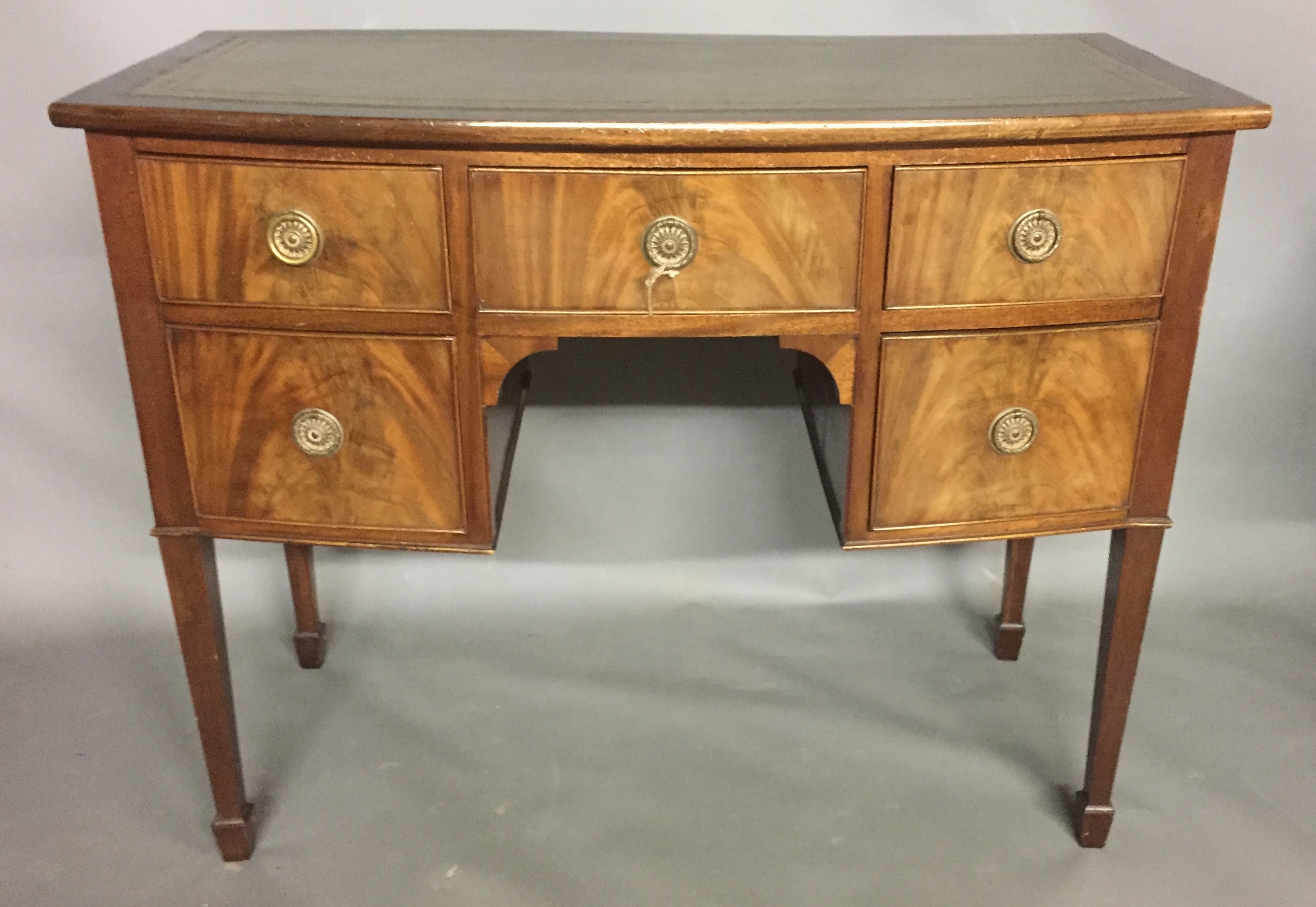 A REGENCY DESIGN MAHOGANY BOW FRONTED SIDE CABINET With green tooled leather writing surface above