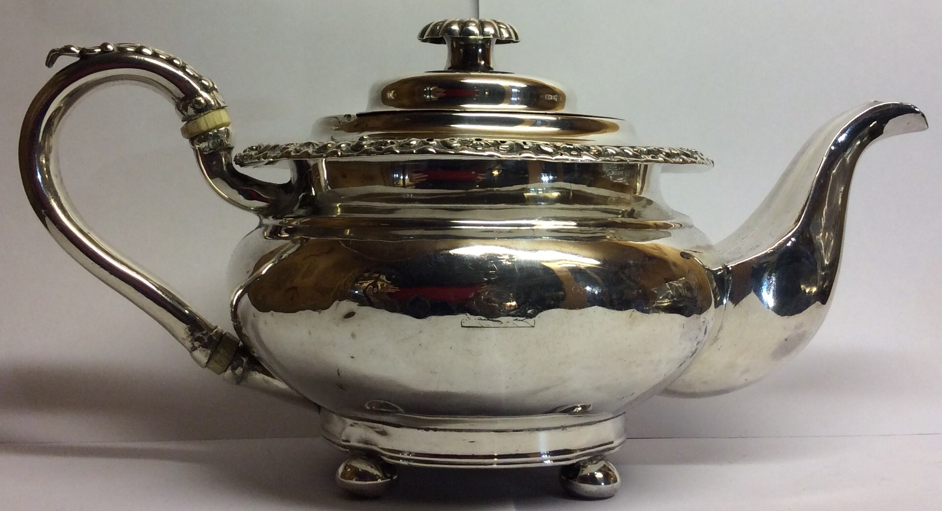 A GEORGIAN SILVER SPHERICAL TEAPOT With acanthus leaf border and handle, fluted finial and bun feet,