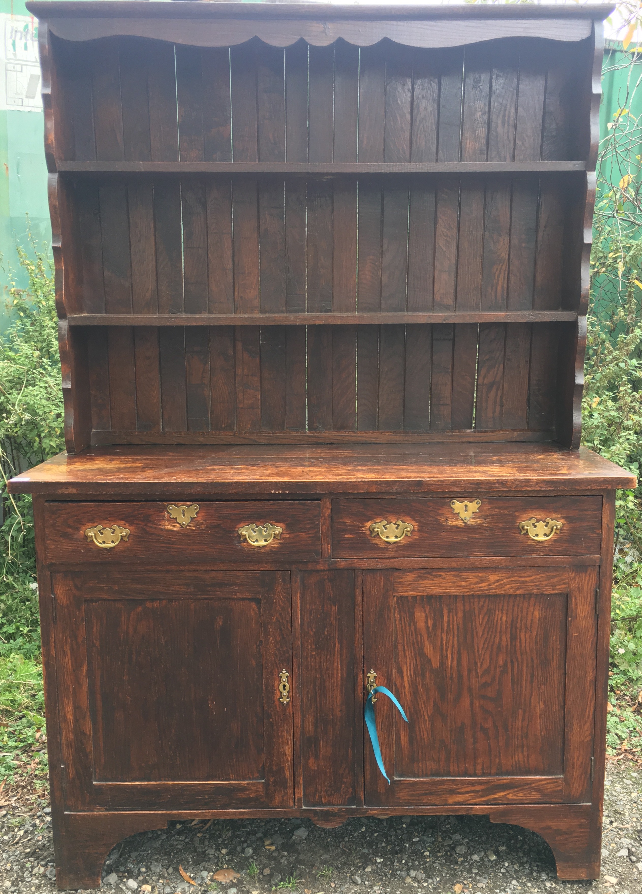 AN EARLY 20TH CENTURY GEORGIAN STYLE OAK DRESSER With open plate rack above two short drawers and