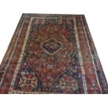 AN ANTIQUE PERSIAN SHIRAZ WOOLLEN RUG OF CARPET PROPORTIONS The central field woven with geometric