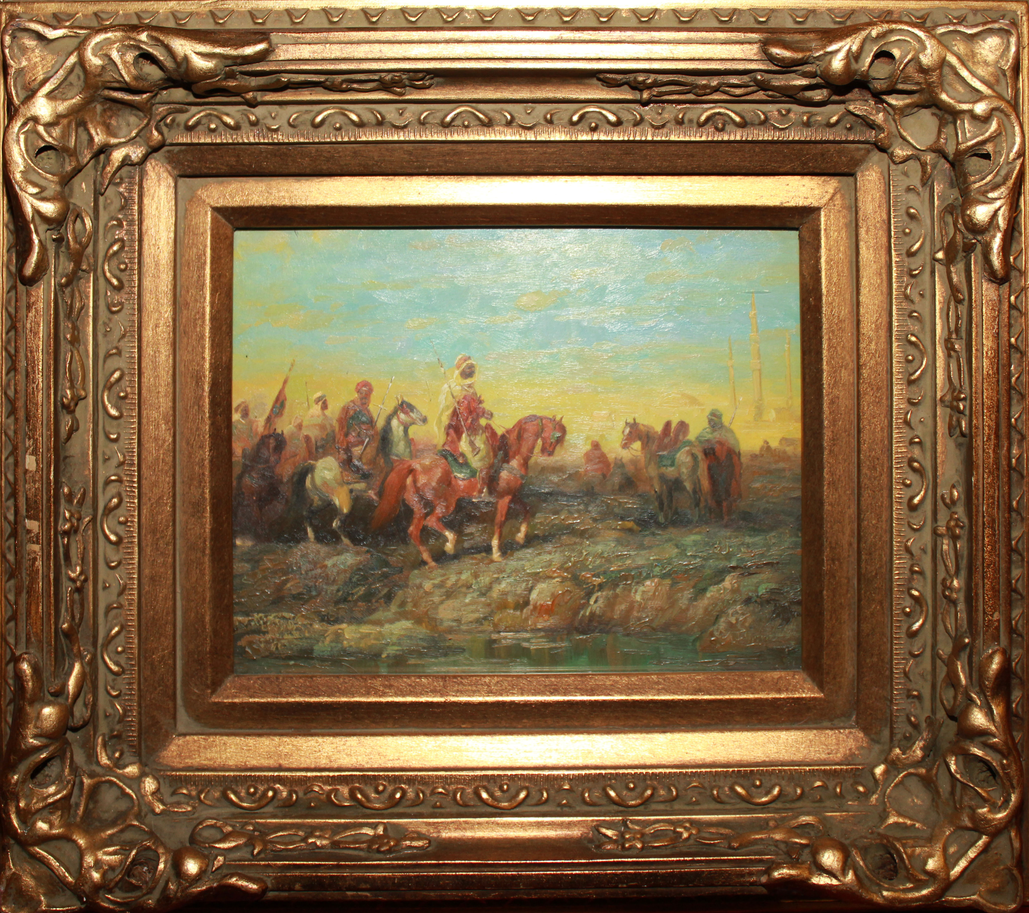 A 20TH CENTURY OIL ON PANEL Landscape, Arab warriors on horseback, held in a carved gilt frame,