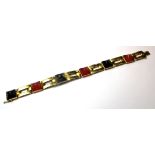 A VINTAGE 18CT GOLD AND GEM SET BRACELET Having a pierced design set with square cut red and black