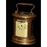A 20TH CENTURY GILT BRASS CYLINDRICAL CARRIAGE CLOCK Having four curved bevelled glass panels and an
