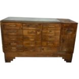 AN EARLY 20TH CENTURY OAK SHOP'S HABERDASHERS CABINET With sixteen drawers and a built-in brass till