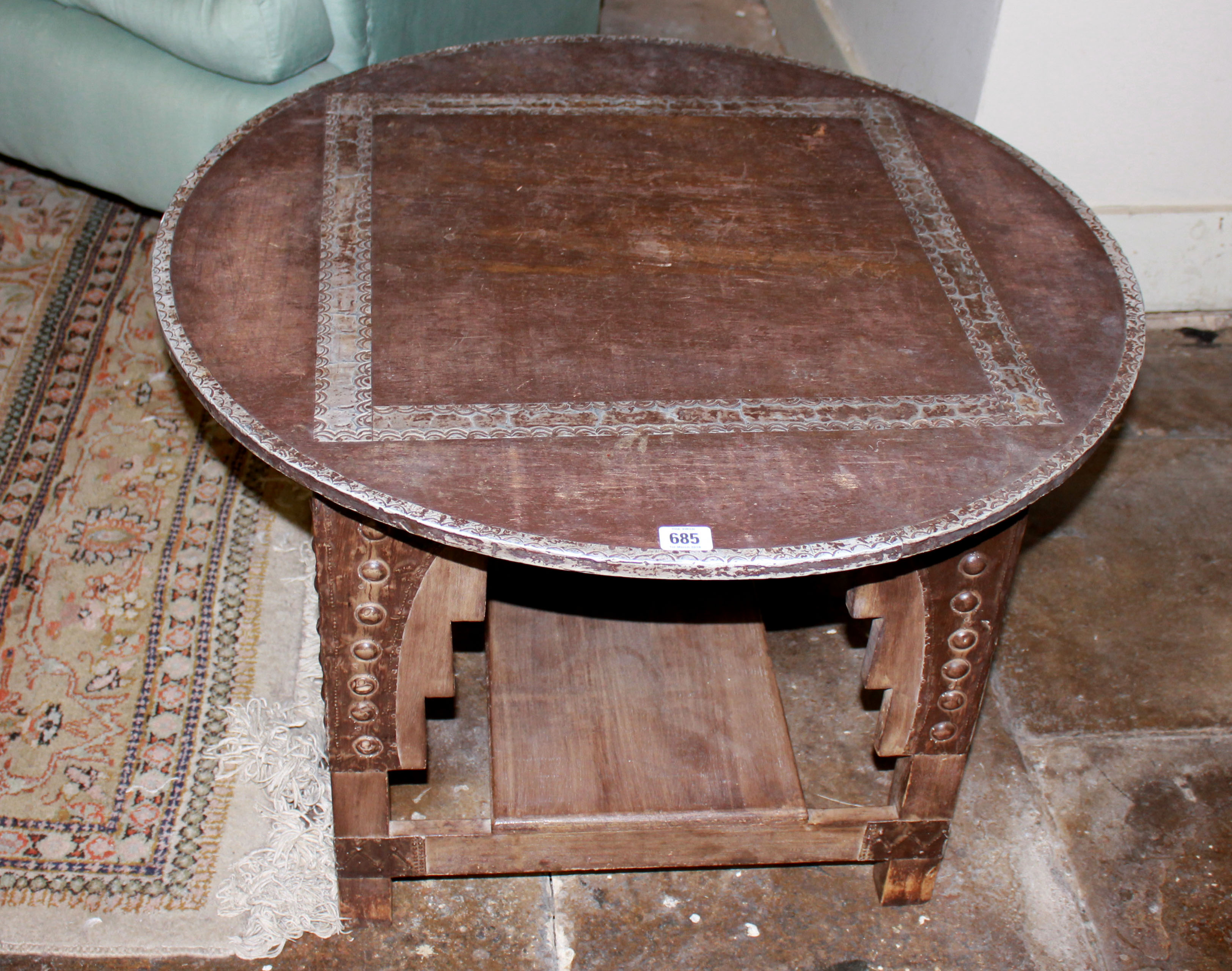 AN EARLY 20TH CENTURY AFRICAN WOODEN TABLE The circular top with metal inlay and edging, raised on
