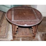 AN EARLY 20TH CENTURY AFRICAN WOODEN TABLE The circular top with metal inlay and edging, raised on