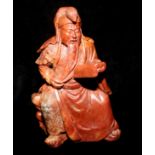 A SOAPSTONE FIGURE OF GUANDI, GOD OF WAR, CIRCA 1800 Carved from a reddish stone and seated on