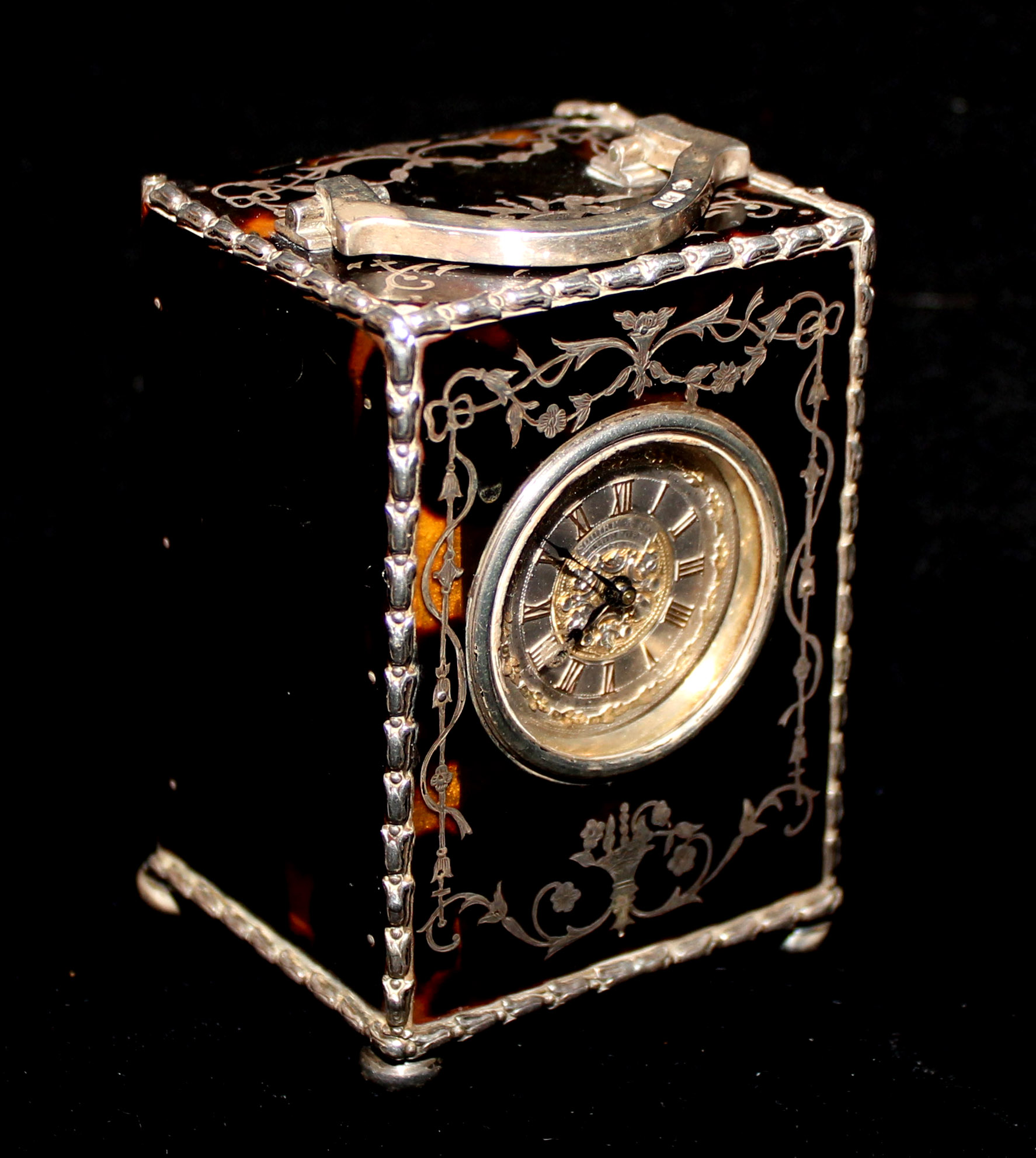 AN EDWARDIAN TORTOISESHELL AND SILVER MINIATURE CARRIAGE CLOCK Having a silver handle and a