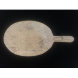 MOUSEMAN, AN OVAL OAK CHEESE BOARD The handle carved with the trademark mouse. (40cm x 21cm)
