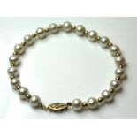 A VINTAGE 9CT GOLD PEARL BRACELET The single row of cultured pearls with spherical gold spacers