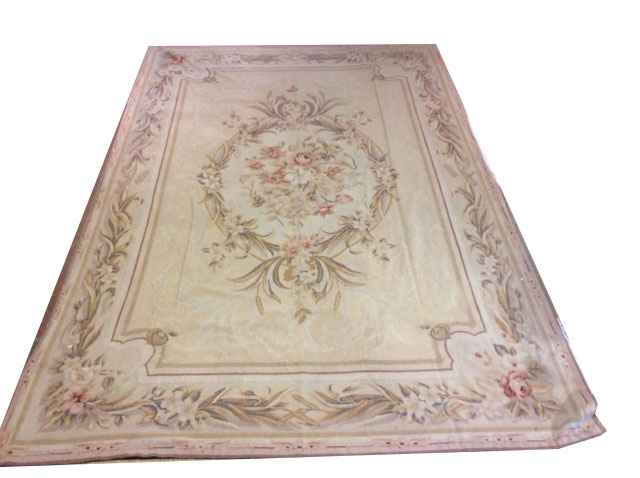 AN ANTIQUE AUBUSSON STYLE WOOLLEN RUG The cream ground with pink floral bouquet to the central field
