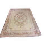 AN ANTIQUE AUBUSSON STYLE WOOLLEN RUG The cream ground with pink floral bouquet to the central field