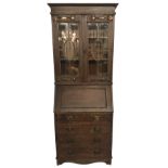 AN ART NOUVEAU OAK BUREAU BOOKCASE With large copper hinges and handles, raised on a shaped plinth