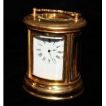 A 20TH CENTURY GILT BRASS CYLINDRICAL CARRIAGE CLOCK Having four curved bevelled glass panels, a
