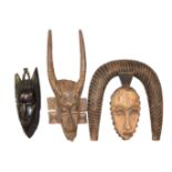 A COLLECTION OF THREE AFRICAN TRIBAL MASKS To include a spiral headdress, one with two horns and a