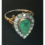 AN 18CT GOLD RING SET WITH A LARGE PEAR SHAPED EMERALD SURROUNDED BY DIAMONDS.