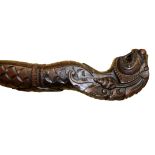 AN ORIENTAL SOFTWOOD CARVED SERPENTINE WALKING STICK Depicting a stylized dragon. (approx 98cm)