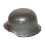 A GERMAN DARK GREEN PAINTED STEEL HELMET Pigskin leather liner present, chinstrap dated 1943,