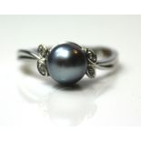 A VINTAGE 9CT WHITE GOLD, BLACK PEARL AND DIAMOND RING The single pearl flanked by two pairs of