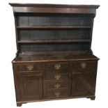 A GEORGE III PERIOD OAK DRESSER With open shelves above an arrangement of drawers and cupboards. (