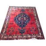 AN AFGHAN WOOLLEN RUG Red ground with blue lozenge central field and running border. (approx