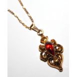 A VINTAGE YELLOW METAL AND GARNET PENDANT Having a tear cut garnet held in a scrolled pierced mount,