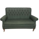 A HOWARD STYLE UPHOLSTERED TWO SEATER SETTEE Having a scrolled back with green fabric cover and