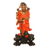 AN ORIENTAL RED LACQUER AND GILT CARVED WOODEN FIGURE OF AN ELDER Holding a gilt Ruyi sceptre,