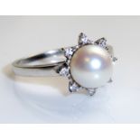 A 14CT WHITE GOLD, PEARL AND DIAMOND SET RING Having a single pearl surrounded by a row of diamonds,