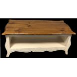 A PINE COFFEE TABLE The ogee shaped top on cream painted base with an open shelf. (w 119cm x d