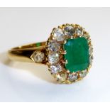 A VINTAGE 18CT GOLD, EMERALD AND DIAMOND CLUSTER RING Having a single faceted emerald surrounded