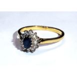 A VINTAGE SAPPHIRE AND DIAMOND CLUSTER RING Having a single oval cut sapphire surrounded by a row of