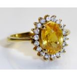 A 14CT GOLD, YELLOW SAPPHIRE AND DIAMOND RING Having a single oval cut sapphire surrounded by a