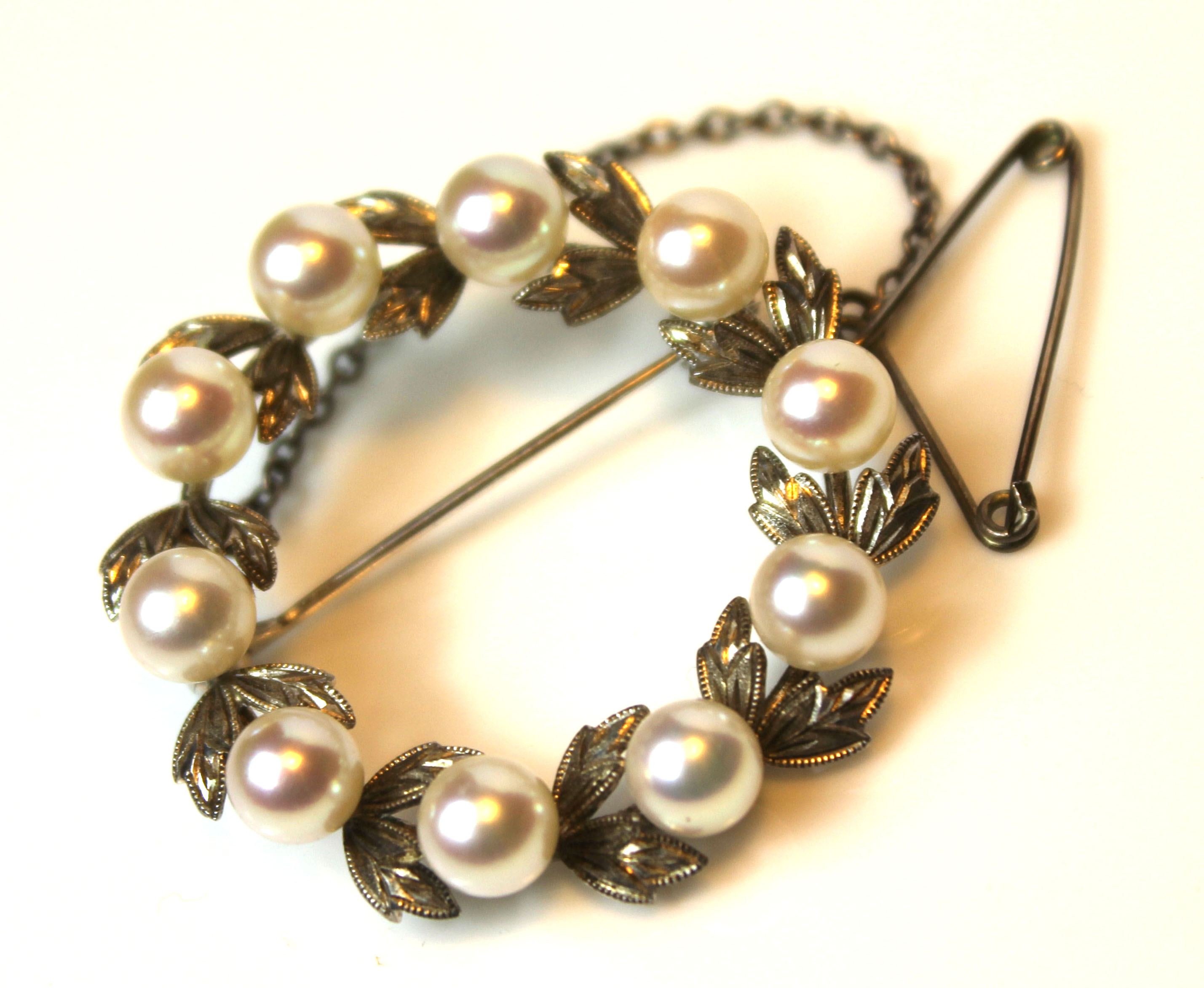 A VINTAGE WHITE METAL AND PEARL BROOCH Laurel wreath design interspersed with leaves. (approx