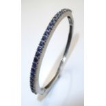 A VINTAGE SILVER AND SAPPHIRE SET BANGLE BRACELET Having a single row of sapphires set in a plain