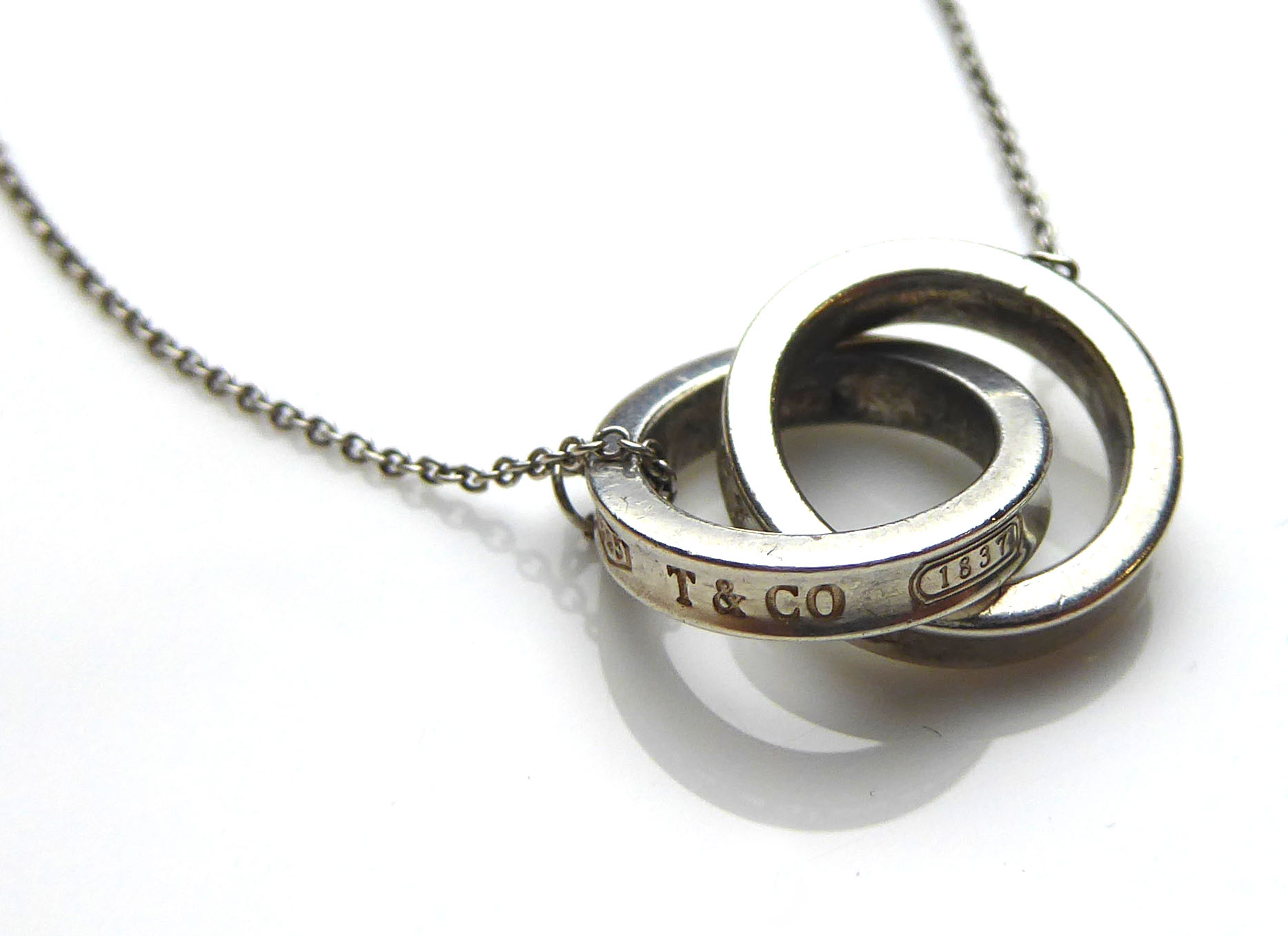 TIFFANY & CO., A SILVER PENDANT AND CHAIN Two consecutive intertwined rings held on a fine link