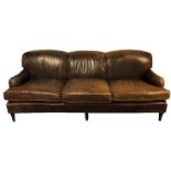 A HOWARD STYLE THREE SEATER SETTEE Of generous proportions, in a tan leather upholstery, raised on