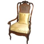 A 19TH CENTURY WALNUT OPEN ARMCHAIR Having carved foliate motifs over rattan back and seat, raised