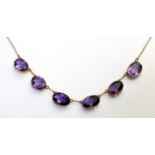 A VINTAGE YELLOW METAL AND AMETHYST NECKLACE Having an arrangement of six oval cut stones, collet