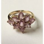 A 9CT GOLD PINK SAPPHIRE CLUSTER RING The oval cut sapphire surrounded by a cluster of pear cut