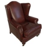 A OXE BLOOD LEATHER UPHOLSTERED WING ARMCHAIR With loose cushions, raised on turned legs with