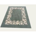 A CONTEMPORARY WOOLLEN RUG the green ground contained in a cream woven floral boarder 243 x 185 cm