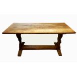 AN EARLY 20TH CENTURY OAK TRESTLE TABLE Having a plank top raised on shaped supports joined by a
