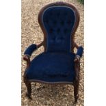 A VICTORIAN MAHOGANY SPOON BACK OPEN ARMCHAIR Upholstered in a button back blue velvet, castors